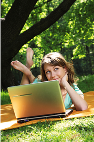 image: smiling woman on lawn with laptop.